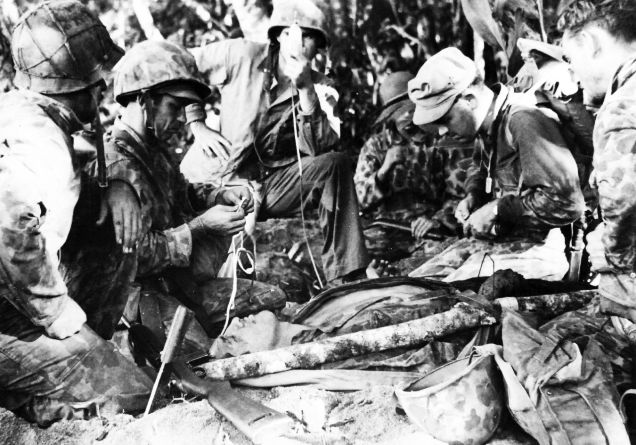 80-G-212235:  Bougainville Campaign, November 1943-August 1945.   November 29, 1943.  In a field hospital wounded Marines are given first aid by doctors and Corpsmen during raid behind Japanese lines on November 29.  Shown:  PhM1c Don A. Lancaster; PhM2c Sidney G. Jeffcoat, who holds a plasma unit; Lieutenant Joseph C. Humbert, MC, USN, Marine Raider surgeon hero preparing a second plasma unit and CphM Claude E. Creech.    Official U.S. Navy Photograph, now in the collections of the National Archives.  (2017/05/02).  