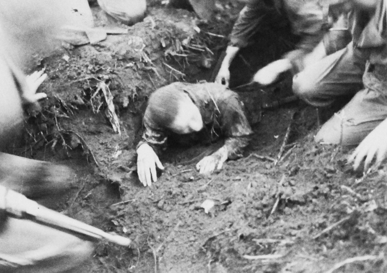 127-GW-971-71486: Battle of Cape Gloucester, New Britain, December 1943-January 1944.   Japanese prisoner.  When Marines blasted a Japanese pillbox on Cape Gloucester, all the Japanese were killed except for one.  Here the Marines are digging him out of the caved-in emplacement.   Photographed by Sylvester, 27 December 1943.   Official U.S. Marine Corps Photograph, now in the collections of the National Archives.   (2014/7/9).