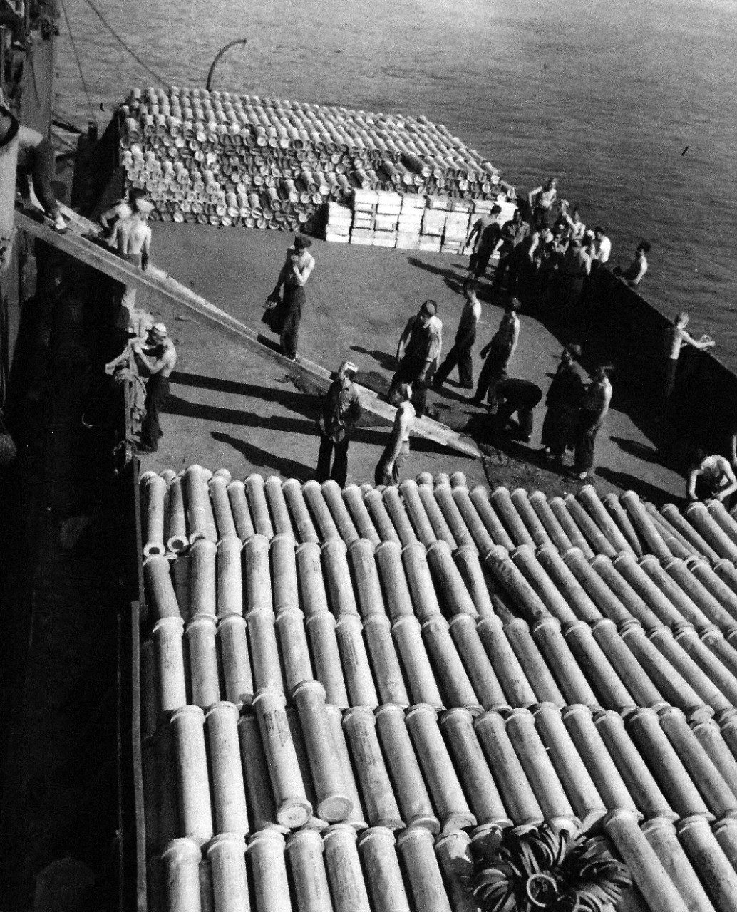 80-G-54565:  Battle of Kula Gulf, July 5-6, 1943.    Files of empty shell cases are loaded on a barge from a U.S. Navy warship which used them in the Battle of the Kula Gulf.     Photograph, August 17, 1943.   Official U.S. Navy photograph, now in the collections of the National Archives.   (2016/07/19).