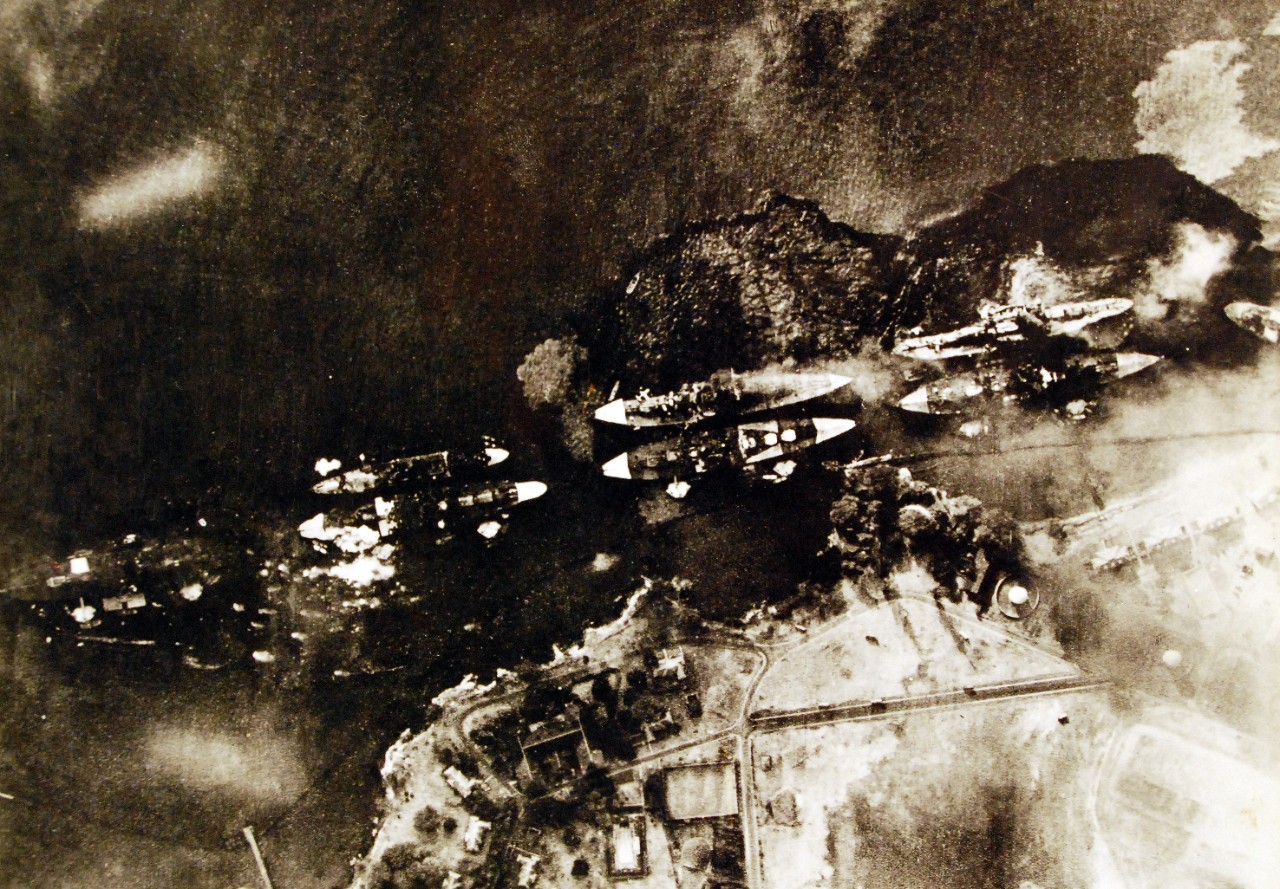 <p>80-G-30551: Pearl Harbor Attack, 7 December 1941. Vertical aerial view of &quot;Battleship Row&quot;, beside Ford Island, during the early part of the horizontal bombing attack on the ships moored there. Photographed from a Japanese aircraft. Ships seen are (from left to right): USS Nevada ; USS Arizona with USS Vestal moored outboard; USS Tennessee with USS West Virginia moored outboard; USS Maryland with USS Oklahoma moored outboard; and USS Neosho, only partially visible at the extreme right. A bomb has just hit Arizona near the stern, but she has not yet received the bomb that detonated her forward magazines. West Virginia and Oklahoma are gushing oil from their many torpedo hits and are listing to port. Oklahoma's port deck edge is already under water. Nevada has also been torpedoed. Japanese inscription in lower left states that the photograph has been officially released by the Navy Ministry. Also at NHHC as NH 50472. From the translated Japanese caption, “Alas, the spectacle of the American battleship Fleet in its Dying Gasp. The attack of our assault force was extremely accurate and achieved direct hits with all bombs. The leading ship of the Oklahoma Class is already half sunk. The Maryland type and the Pennsylvania type are blowing up from several direct hits. The ships crumble and their hulls are twisted and keeling over. Crude oil gushes forth fearfully. This view of the wretched enemy’s capital ships which were converted into a sea hell was photographed from directly overhead by the heroes of our calm, valorous attack force.” (9/22/2015).</p>

