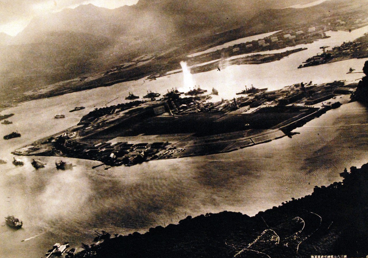 80-G-30554:  Pearl Harbor Attack, 7 December 1941.  Photograph taken from a Japanese plane during the torpedo attack on ships moored on both sides of Ford Island. View looks about east, with the supply depot, submarine base and fuel tank farm in the right center distance. A torpedo has just hit USS West Virginia on the far side of Ford Island (center). Other battleships moored nearby are (from left): Nevada, Arizona, Tennessee (inboard of West Virginia), Oklahoma (torpedoed and listing) alongside Maryland, and California.  On the near side of Ford Island, to the left, are light cruisers Detroit and Raleigh, target and training ship Utah and seaplane tender Tangier. Raleigh and Utah have been torpedoed, and Utah is listing sharply to port.  Japanese planes are visible in the right center (over Ford Island) and over the Navy Yard at right. Japanese writing in the lower right states that the photograph was reproduced by authorization of the Navy Ministry.  Also at NHHC as NH 50930.  This image also exists at the Library of Congress.     Original Japanese caption reads, “Full View of Ford Island gasping under the attack of our Sea Eagles.   This distant view of Ford Island immediately after the attack of our assault force shows the enemy capital ships lined up on the opposite sides of the island.  In the foreground is a cruiser fleet, including the battleship Utah.  The enemy ships around the island have all become tempting targets for our Sea Eagles.  In the upper right, clearly appear the outlines of two of our Sea Eagles who are carrying out a daring low-level attack, reminiscent of the performance of the gods.”(9/22/2015).