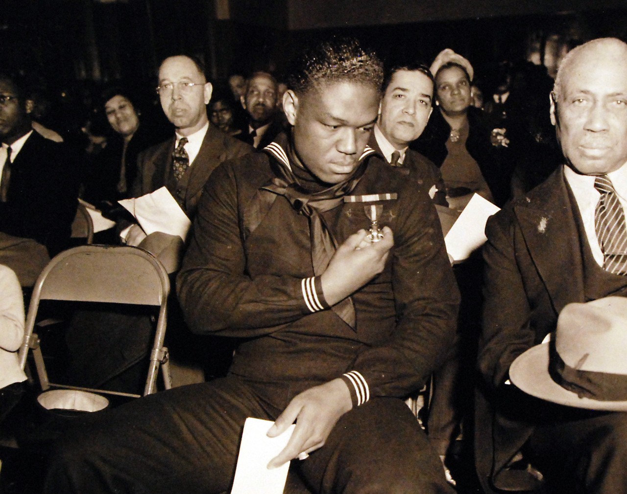 80-G-294803:  Doris Miller, Mess Attendant First Class, USN.  During his visit to the Naval Training Station, Great Lakes, Illinois, 7 January 1943.  He is holding the Navy Cross medal, awarded for heroism during the Pearl Harbor Attack, 7 December 1941.  Official U.S. Navy Photograph, now in the collections of the National Archives.  