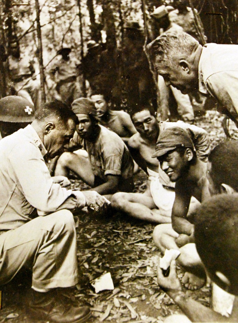 Lot-9432-16: Battle of Bataan, January –April 1942.  U.S. Army Officer Questions Japanese Taken Prisoner at Bataan.  Japanese prisoners of American and Filipino forces on Bataan Peninsula, in the Philippines, are questioned by Brigadier General Clinton Pierce, (left), of the U.S. Army.  Note that one of the prisoners (lower right-hand corner) is eating a sandwich.  The picture is one of the last to reach the outside world before the heroic Bataan defenders finally succumbed to disease, hunger and vastly overwhelming numbers.   Office of War Information Photograph, 9-15 April 1942.  Original photograph is small.  Courtesy of the Library of Congress.  (2015/12/18).