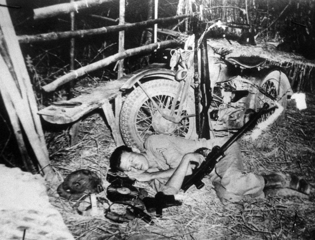 LC-Lot-9432-21: Battle of Bataan, January-April 1942.  They Sleep on Bataan With Weapons Handy.  Weary from long hours of vigilance in the Battle of Bataan, a U.S. Army dispatch rider takes a nap beside his machine at the end of a run, still cradling his gun.  The picture, taken during the last days of the Philippine-U.S. forces heroic four-months stand, tells the story of what overpowered the brave but badly out-numbered men – sheer exhaustion.  That, together with depleted stocks of arms and ammunition, together with dwindling supplies of food, finally terminated the battle.  Office of War Information Photograph, 9-15 April 1942.  Original photograph is small.  Courtesy of the Library of Congress.  (2015/12/18).