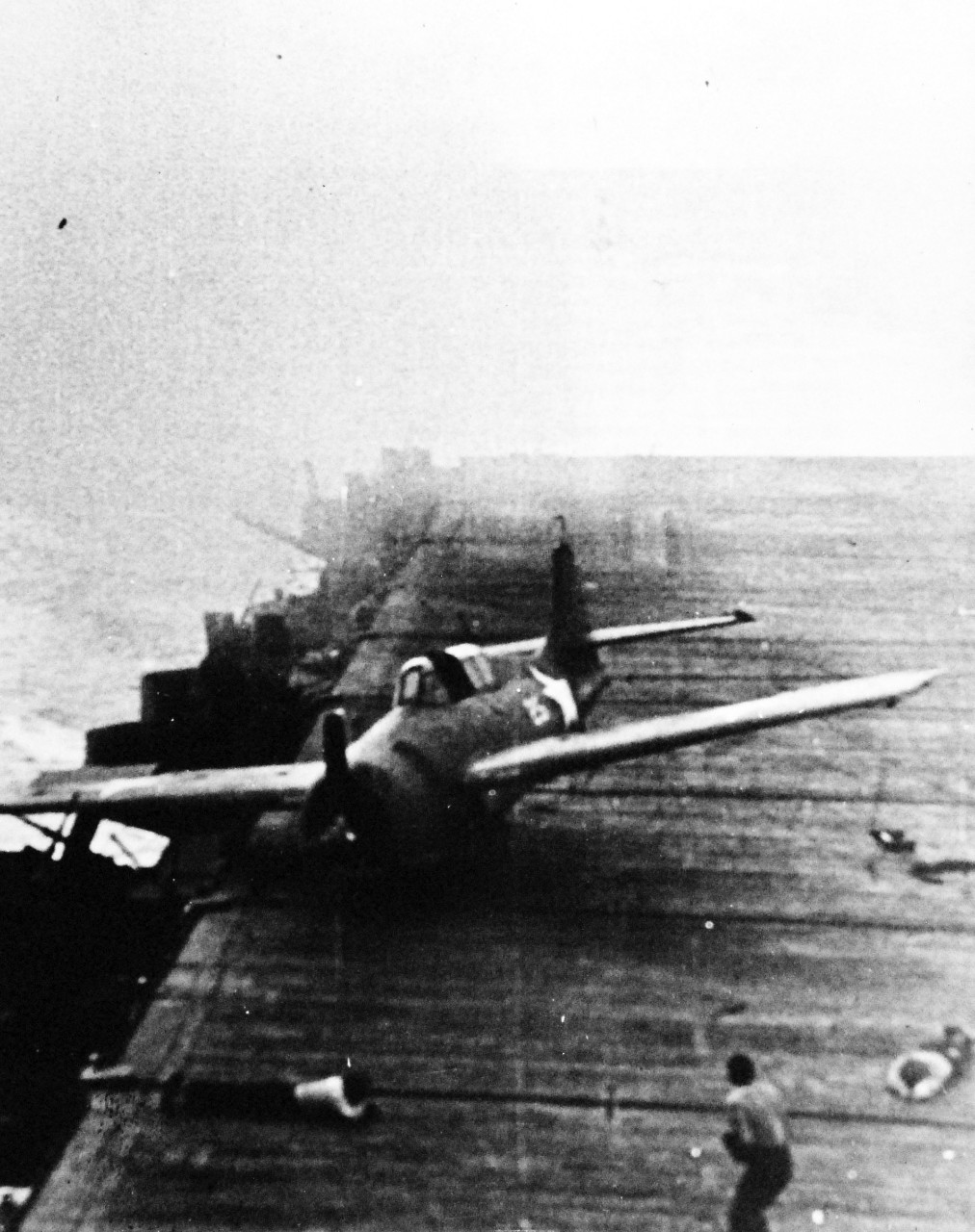 80-G-42561:  Battle of Santa Cruz Islands,  26 October 1942.   Scene from the flight deck of USS Enterprise (CV 6).  Lurching to the edge of the flight deck as a result of a near miss by a Japanse bomb, this US Navy plane finally halts just before plunging into a gun gallery.  Note, a member of the crew hitting the deck in order to avoid the swerving wings of the plane.   (8/13/2014).