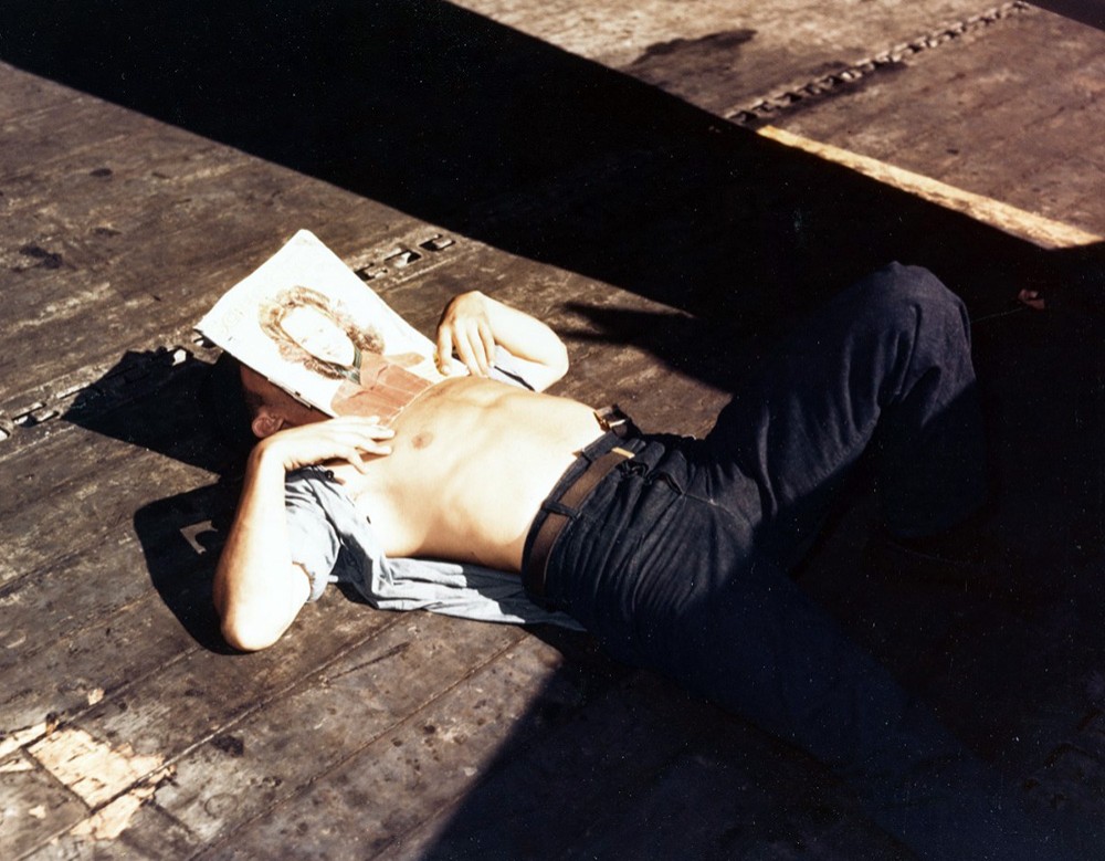 USS Lexington (CV-16), November 1943. Flight deck crewman catches a quick nap, and a bit of sun, during a lull in operations, taken during the Gilberts Campaign. Photographed by Edward Steichen. Official U.S. Navy Photograph, now in the collectio...