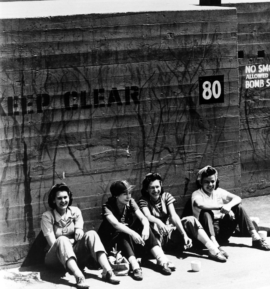 Vega (Lockheed) Aircraft Plant, Burbank, California.    Four women workers sit against a bomb shelter wall during their lunchtime break, August 1943.  Photographed by Lieutenant Charles Fenno Jacobs, USNR.  Official U.S. Navy Photograph, now in the collections of the National Archives, 80-G-412639.