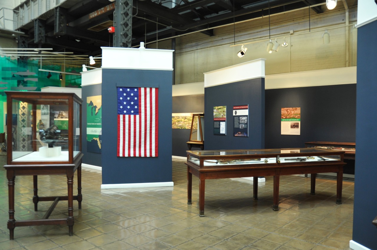 NMUSN-5154: War of 1812, From Defeat to Victory exhibit, 2014. Temporary exhibit area. Note the replica of the Star Spangled Banner Flag. This exhibit was part of the 200-year anniversairy exhibit to commemorate the U.S. Navy’s involvement agains...