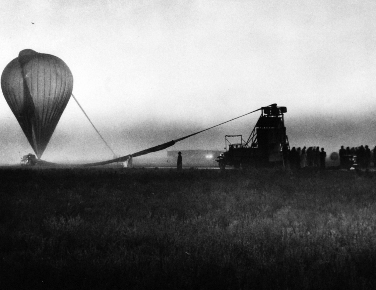 80-G-709969:  Operation Stratoscope.  The nearly inflated balloon, the cargo parachute and the instrument payload mounted on the rear of the launching vehicle are visible through the fog on the morning of the launching, September 25, 1957.  Official U.S. Navy photograph, now in the collections of the National Archives.     