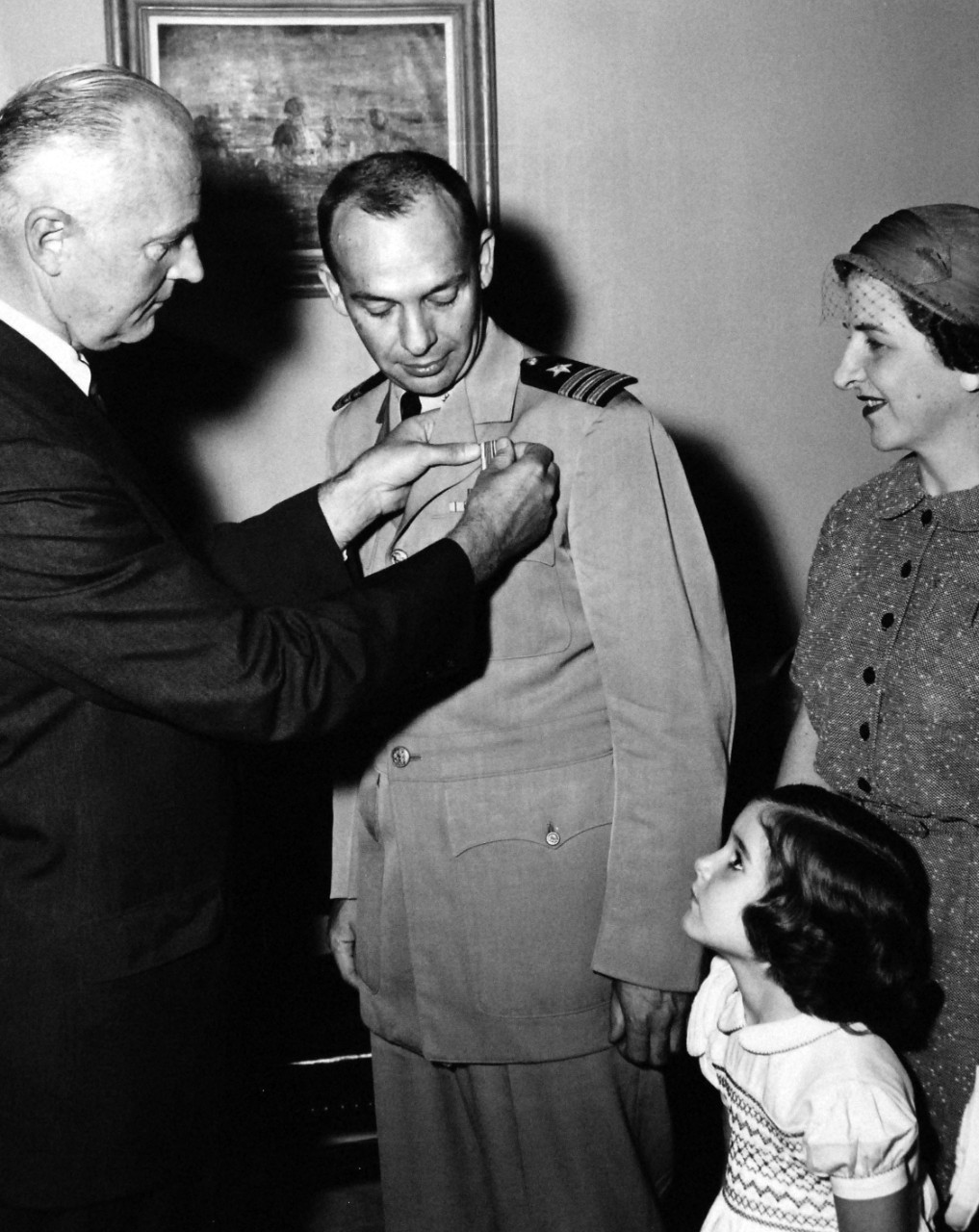 USN 710503:   Naval Balloonist Commander Ross Receives Distinguished Flying Cross.    Commander Malcolm D. Ross, USNR, Naval Balloon Pilot, receives the Distinguished Flying Cross from James H. Wakelin, Assistant Secretary of the Navy for Research and Development.  Mrs. Ross, the Commander’s wife and daughter, Jane, witnessed the 25 August 1959 ceremony.  The citation was awarded “for extraordinary achievement in aerial flight as command pilot of a two-man Navy balloon and gondola during a daring and hazardous ascent into the upper stratosphere on July 26-27, 1958.  In addition to setting a new unofficial world endurance record for sustained flight into the stratosphere of thirty-four hours and thirty-nine minutes, he also successfully completed approximately twenty-seven other scientific experiments conducted aloft as a scheduled part of the flight, attracting widespread public attention and acclaim.  By his outstanding professional skills, courage, and inspiring efforts, Commander Ross made a highly significant contribution to man’s scientific conquest of space.”  Official U.S. Navy photograph, now in the collections of the National Archives.     
