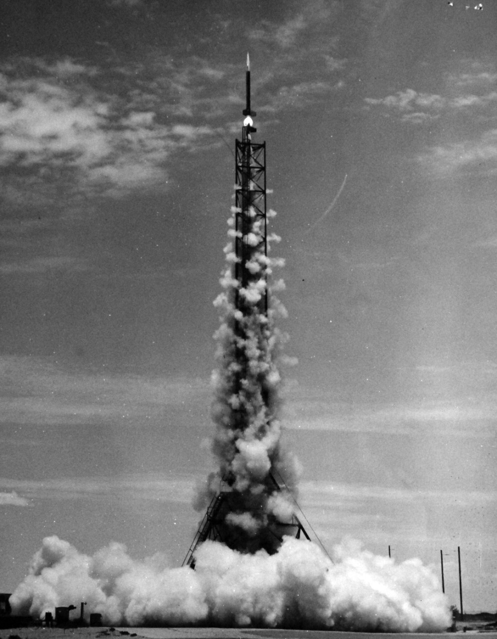 330-PS-7909 (USN 709626):   The Navy Research Rocket, Aerobee Hi, is fired from its launchers at U.S. Naval Ordnance Missile Test Facility, White Sands Proving Ground, New Mexico, the Aerobee Hi carried 135 pounds of radio devices 163 miles above the Earth, June 29, 1956, to set a new altitude record for an American-built “boosted” rocket.  Less than a minute after take-off, the pencil-slim 23-foot rocket had attained a maximum speed of 4435 miles per hour.  The primary experiment performed with this research rocket was the measurement of various physical characteristics of the Ionosphere, that part of the Earth’s atmosphere at an altitude of 35 miles.  Photograph released July 3, 1956.  Official U.S. Navy Photograph, now in the collections of the National Archives.  