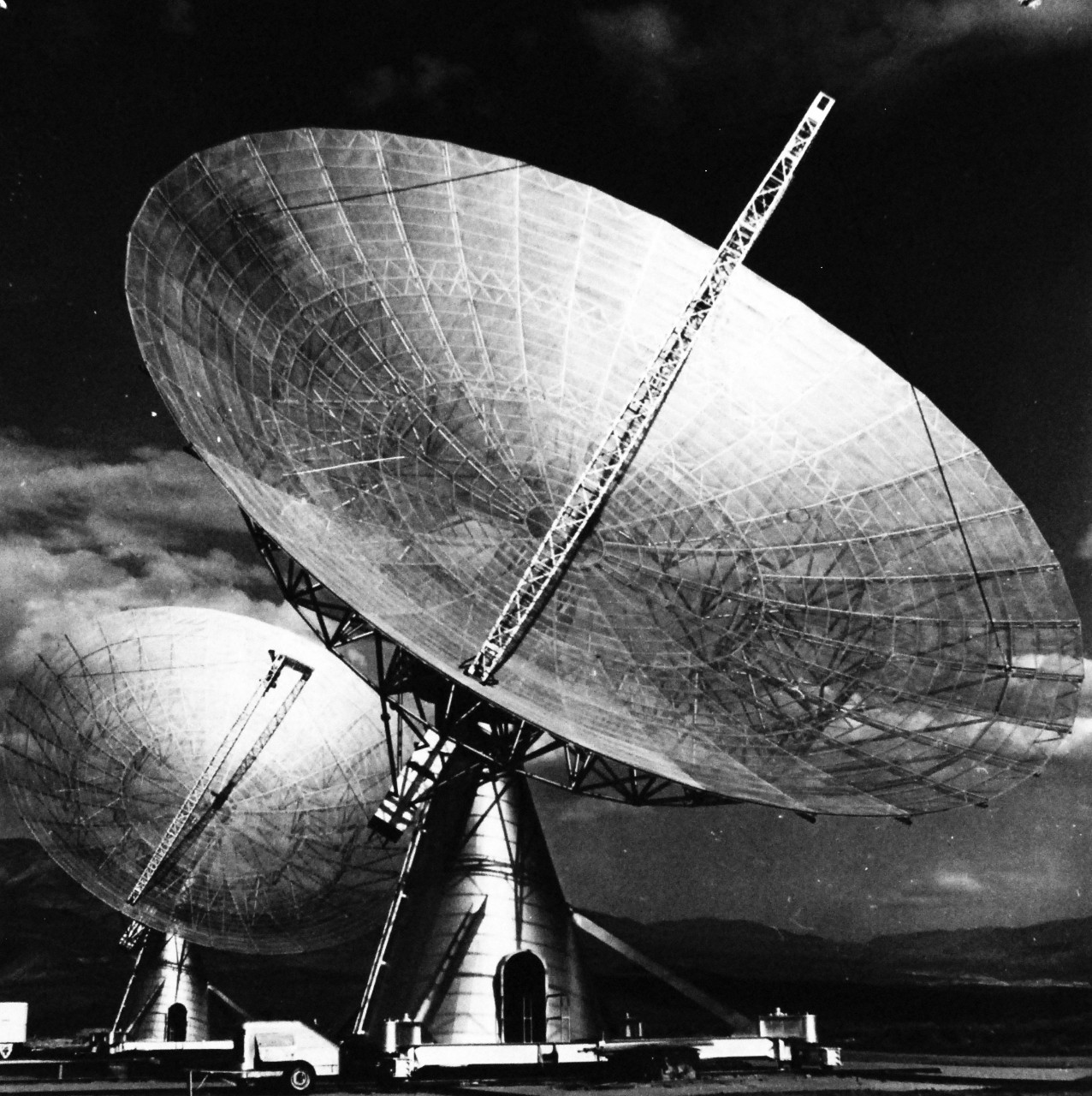 USN 710653:   U.S. Navy Telescope Locates New Radio Sources in Space, March 1960.  Nine Radio sources from outside our galaxy have been located in the first two months of operation of a new Navy twin radio telescope.  Up to the end of 1959, when the Navy telescope went into full operation, only five other radio sources of the more than 100 detected outside the Milky Way had been precisely located and identified by all the radio telescopes of the world.  The giant instrument was built by and is operated by the California Institute of Technology under contract with the Office of Naval Research as part of the Navy’s Radio Astronomy program.  Located in a valley 259 miles from Los Angeles, the radio telescope consists of two 90-foot parabola antennas mounted on a 1600-foot long railroad track running east-west.  Working in tandem, the twin dishes produce a resolving power (i.e. ability to pinpoint radiating objects in space separated by small angular distances).  Greater than any known radio telescope in operation or under construction.  Currently, the radio telescope is being used to try to identify other radio sources in space.  The twin dishes can also be used to study planets and other large celestial bodies.  Two planets can be studied at the same time by using such each dish independently.  The new radio telescope may also be use in resolving the conflict of opinion as to whether the planet Jupiter is surrounded by a corona or by a Van Allen type radiation belt.  Photograph released 22 March 1960.  Official. U.S. Navy Photograph, now in the collections of the National Archives.  