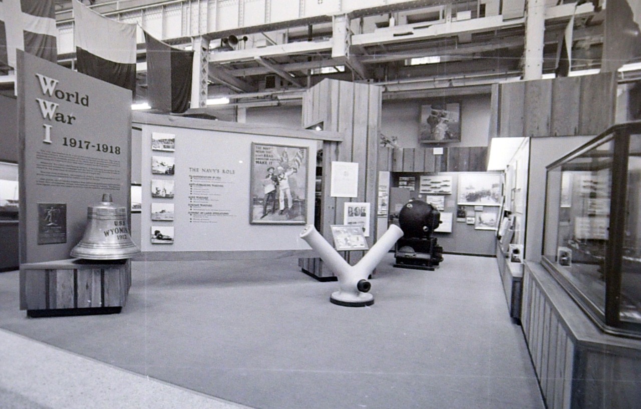 NMUSN-1255: World War I exhibit area, mid-1970s View shows the entrance, Y-Gun, and Mk6 Mine, along with the USS Wyoming bell. Original is a film strip. National Museum of the U.S. Navy Photograph Collection.