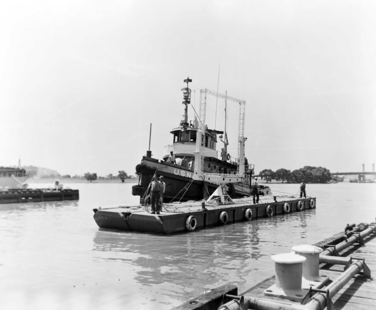 NMUSN-1014:   XAF Radar Antenna, 1960s.   Being delivered to the Washington Navy Yard for display.  Note the U.S. Navy tug alongside a small thin barge carrying the radar antenna.  The tug appears to be USS Wahtah (YTB-140).  This radar was the first shipboard radar to be installed onboard a U.S. Navy ship, USS New York (BB-34).  Surviving World War II, it was brought to the Washington Navy Yard where it was on exterior display until the mid-1980s where it was placed into storage.   Following conservation, the radar is now on display at the National Electronics Museum, Linthicum, Maryland.    Original is a black and white negative.   National Museum of the U.S. Navy Photograph Collection.