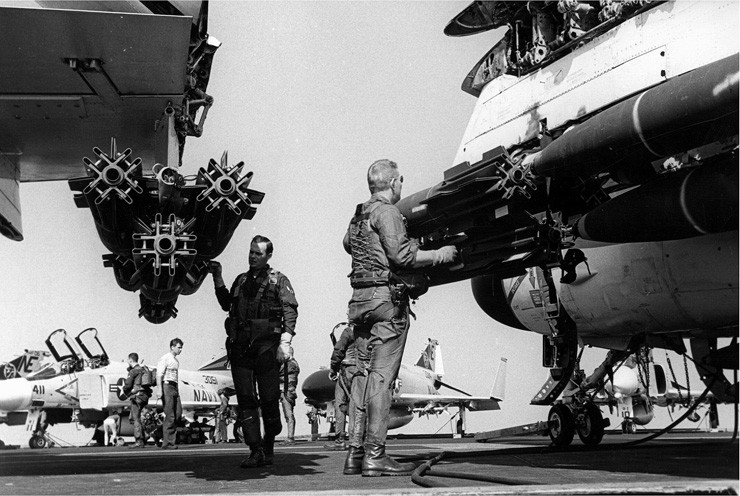 Photo of pilots inspecting ordnance on their A-6 Intruder aircraft.