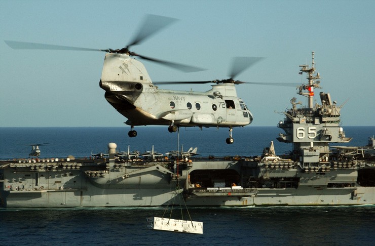Photo of CH-46 Sea Knight helicopter transporting cargo to USS Enterprise during vertical replenishment at sea.