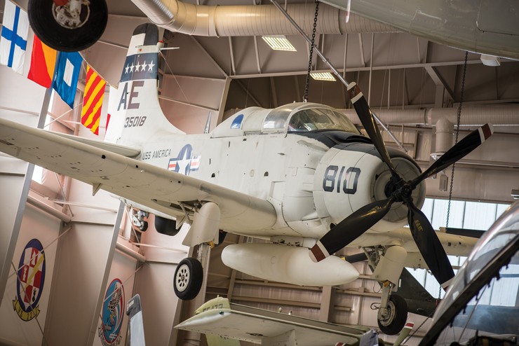 Photo showing the EA-1F Skyraider on display at the museum hanging in Hangar Bay One.