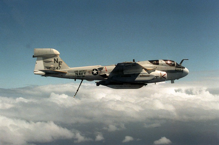 Photo showing an EA-6B Prowler aircraft in flight with its tailhook in the down position.