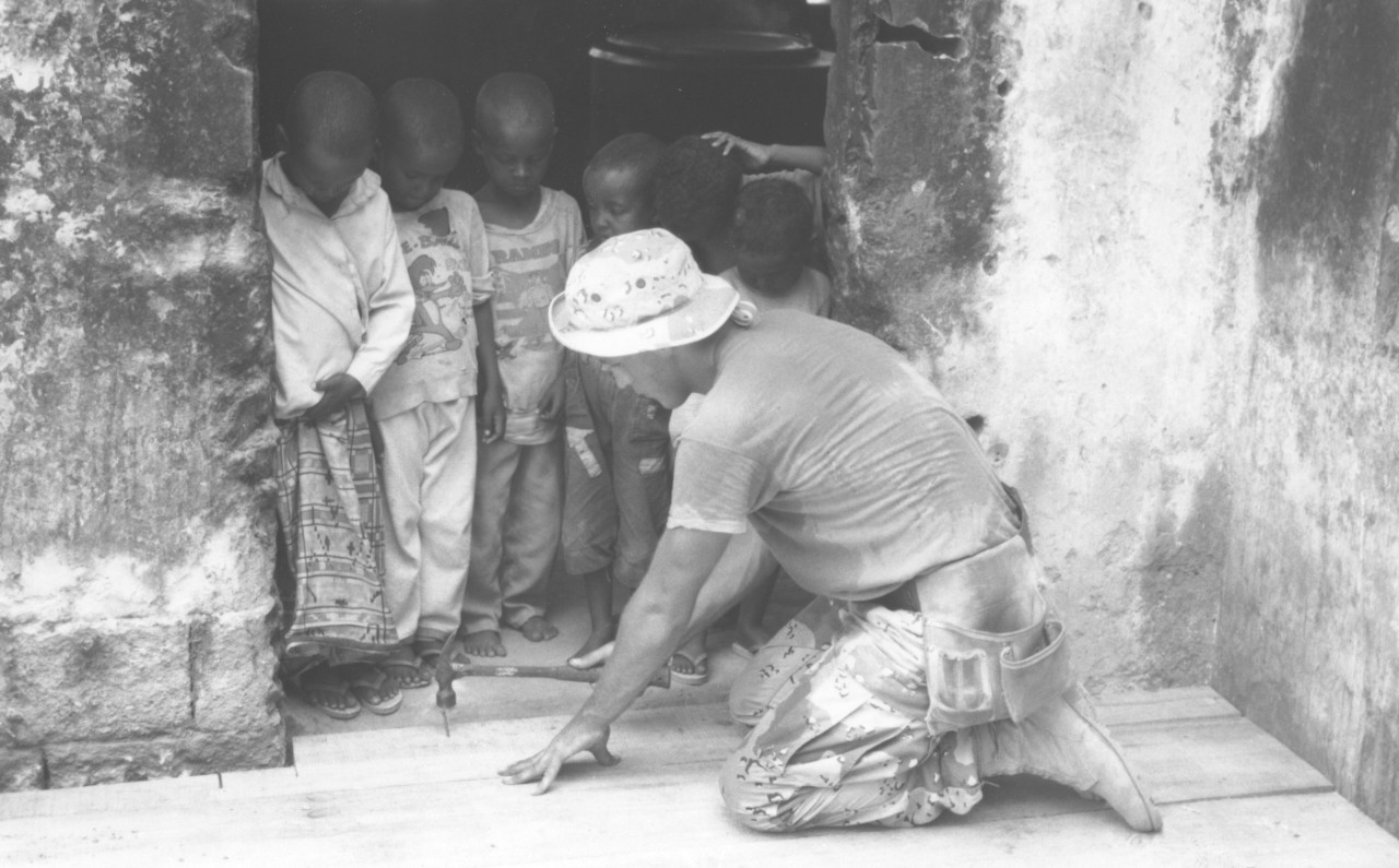 A Seabee from NMCB-40’s Air Detail aids a local orphanage by installing a floor, January 1993.  