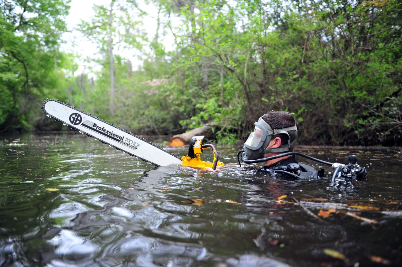 Construction Mechanic 2nd Class Adam Griffin begins to saw a submerged log while clearing a river during a field training exercise for Underwater Construction Team (UCT) 1. UCT-1 is conducting their field training exercise and final evaluation ph...