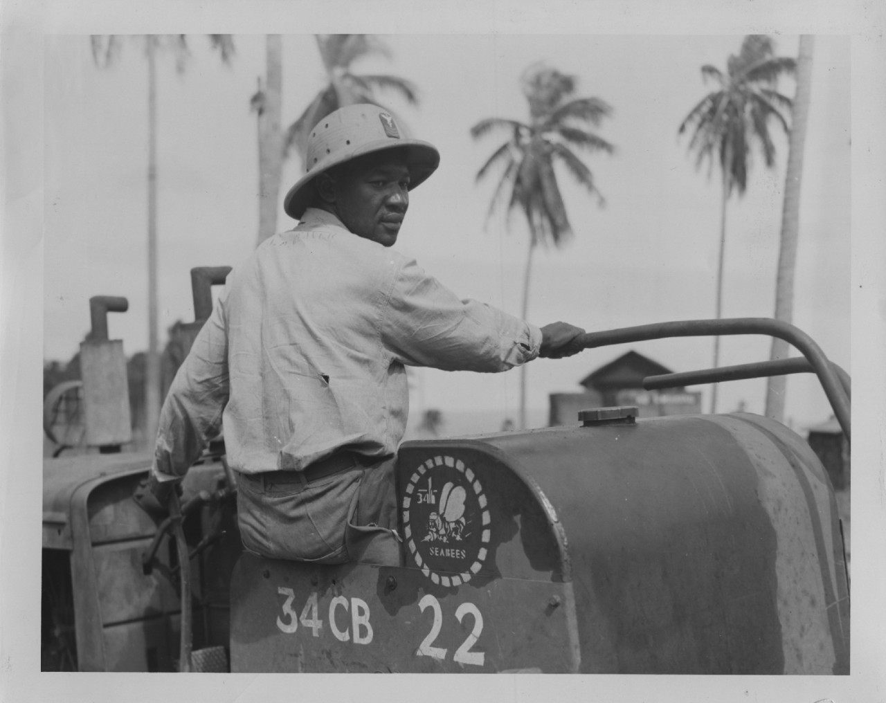 34th Naval Construction Battalion Seabee operating a bulldozer, 1943. Image is black and white.