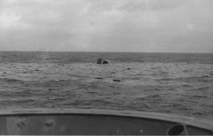 Sinking hull portion of Frederick C. Davis (DE-136), torpedoed in the western Atlantic by U-546 on 24 April 1945. Surviving crewmembers float nearby. 