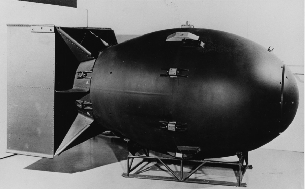 Black-and-white photograph of the “Fat Man” type atomic bomb, the kind detonated over Nagasaki, Japan, on 9 August 1945. The bomb is 60 inches in diameter and 128 inches long. Here, the bomb is photographed indoors. It rests on its side on a low ...