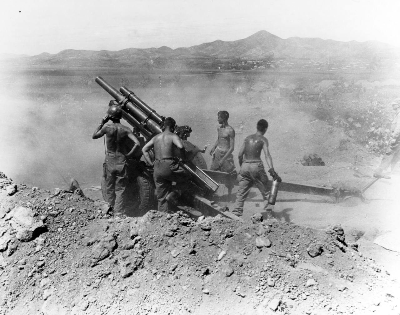 Gun crew of the 64th Field Artillery Battalion, 25th Infantry Division, fire a 105mm howitzer on North Korean positions near Uirson, South Korea, 27 August 1950. Photographed by PFC Wayne H. Weidner. Photograph from the Army Signal Corps Collecti...
