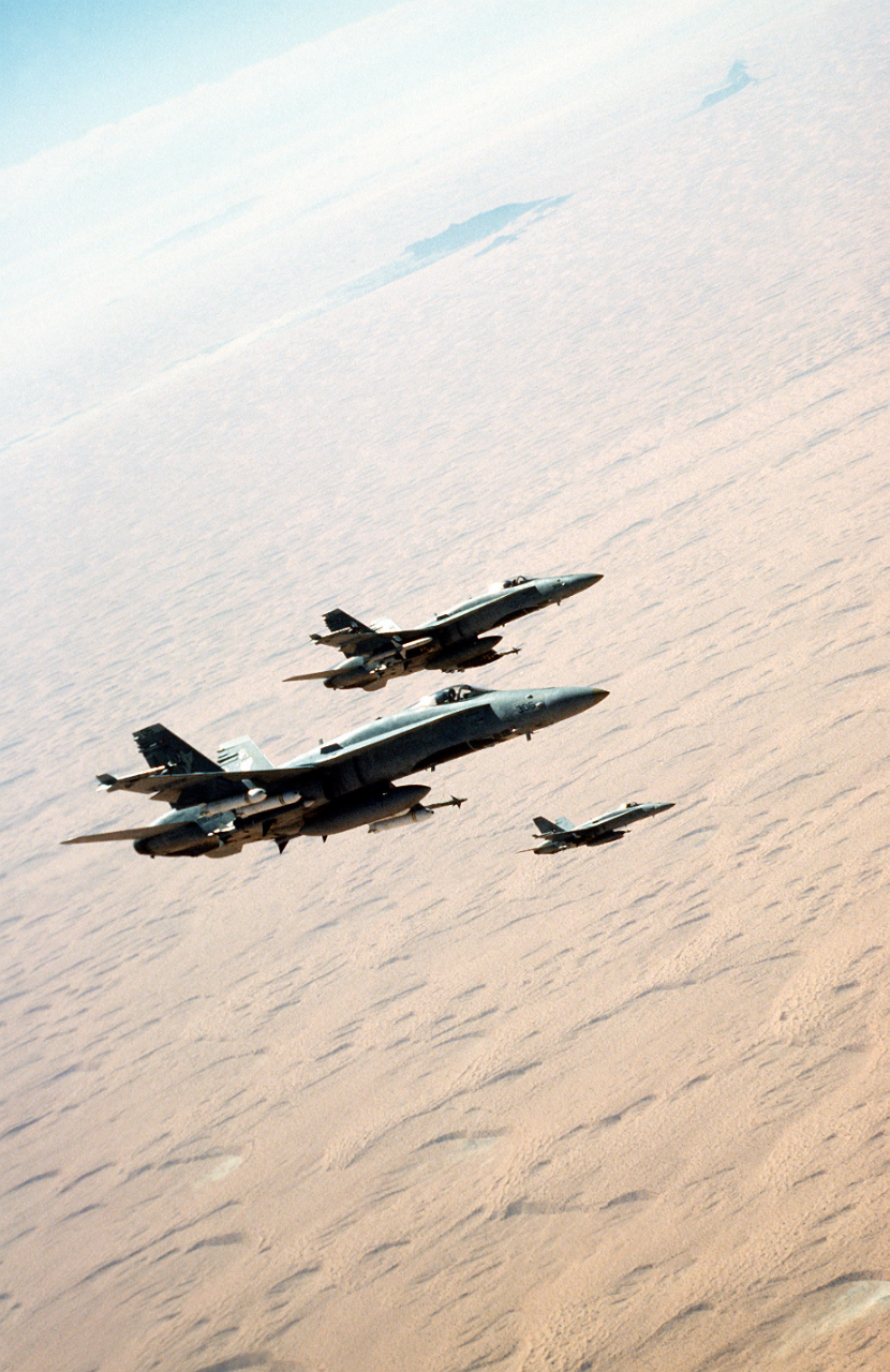 Hornet aircraft flying in formation over desert.