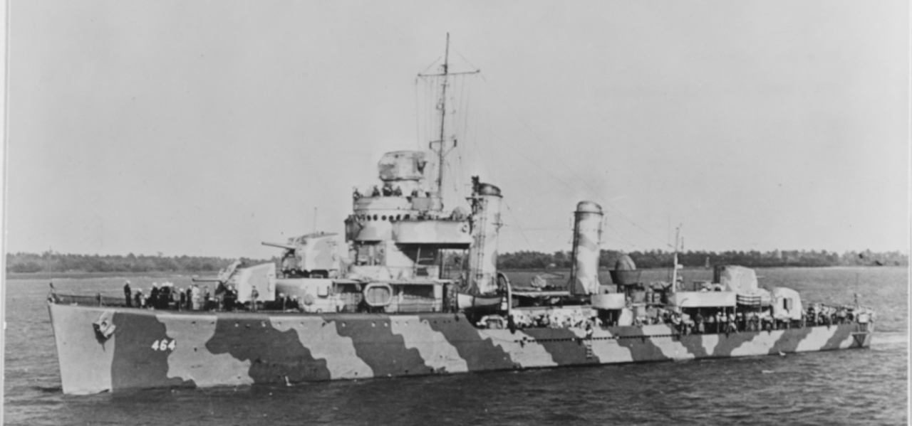 Black and white photograph of destroyer painted with camouflage while underway.  