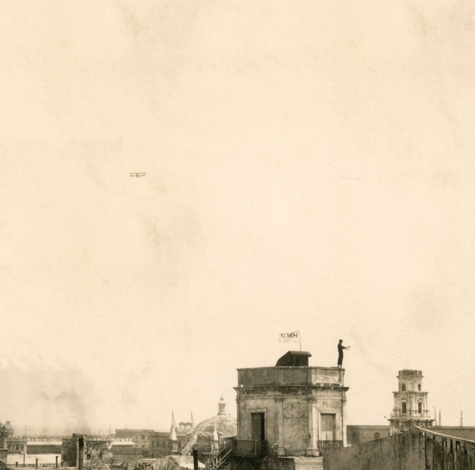 Biplane flying over a city. 