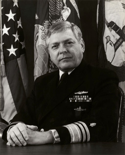 official photo of man in Navy uniform with his hands crossed in front of him on a desk