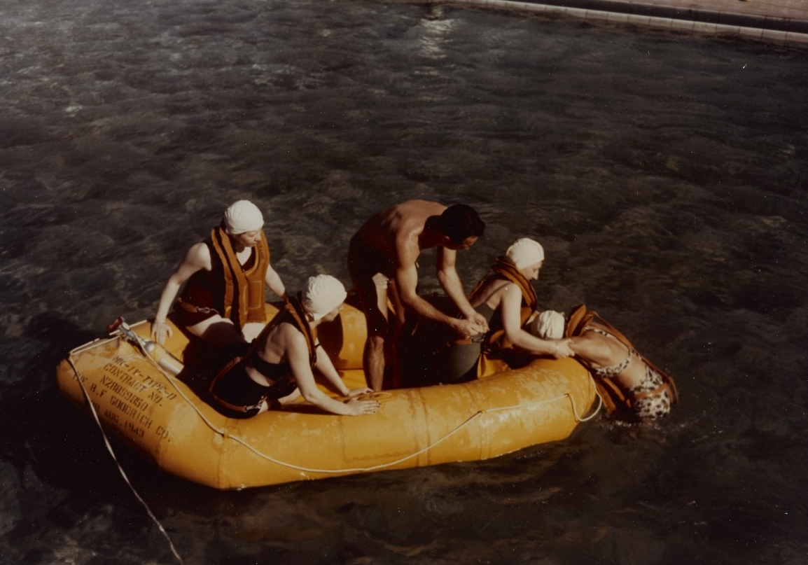 Four women and one man help pull another woman into a raft