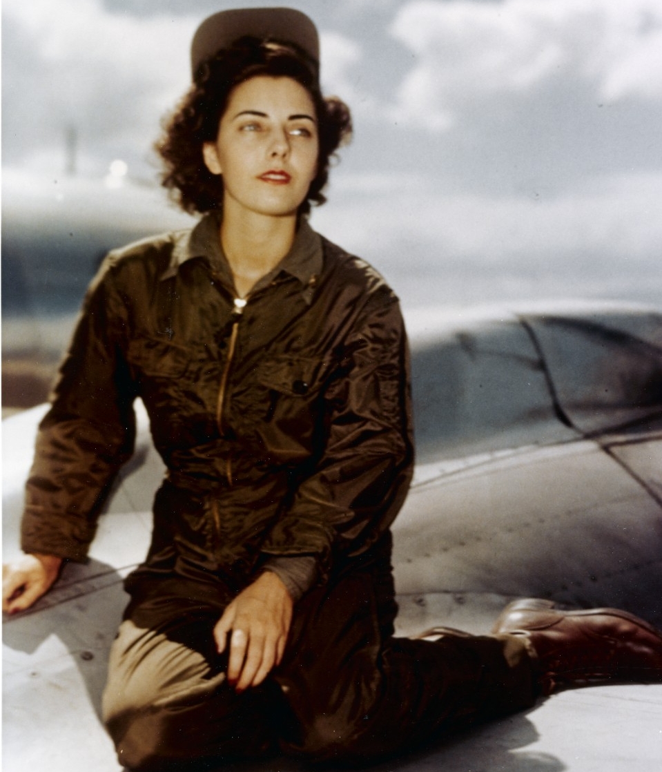 woman in flight uniform sits on wing of plane