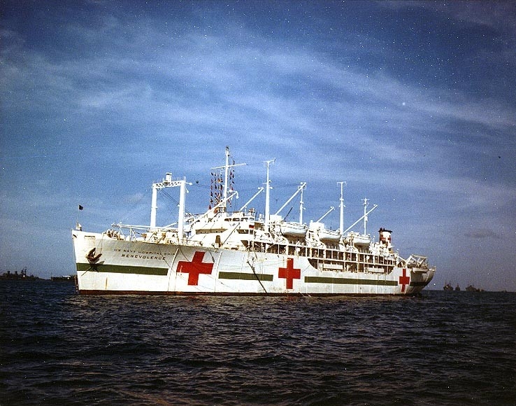 A white ship with two red crosses floats at sea