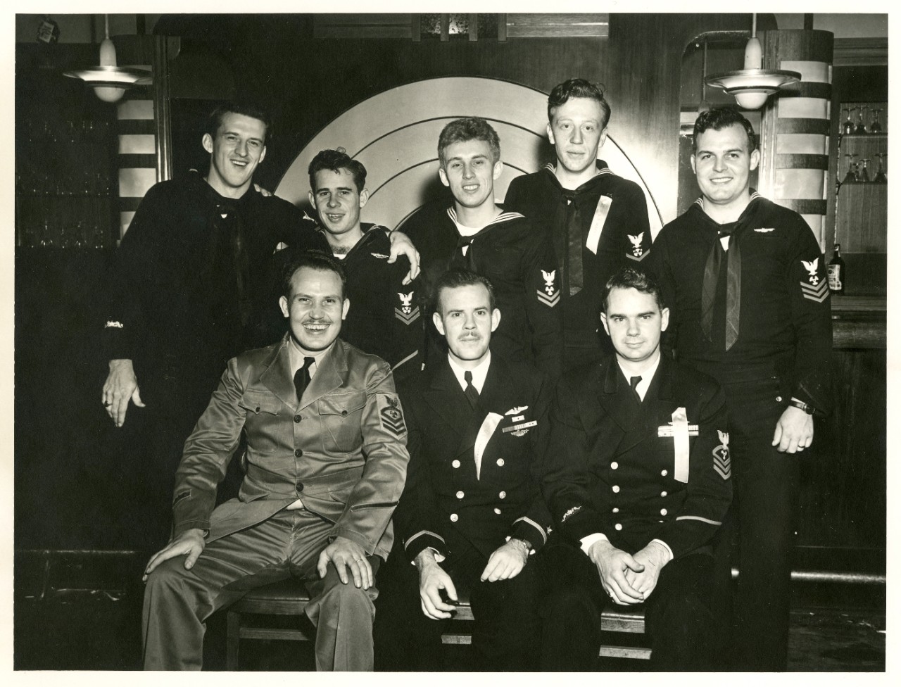 <p>Group photo of eight sailors in dress blue uniforms wearing the submarine warfare insignia</p>