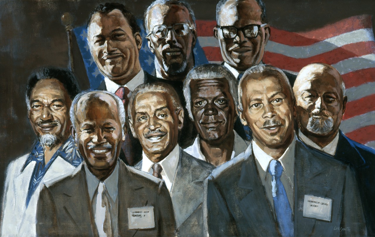 Two rows of Black men in suit jackets with an American flag in the background.