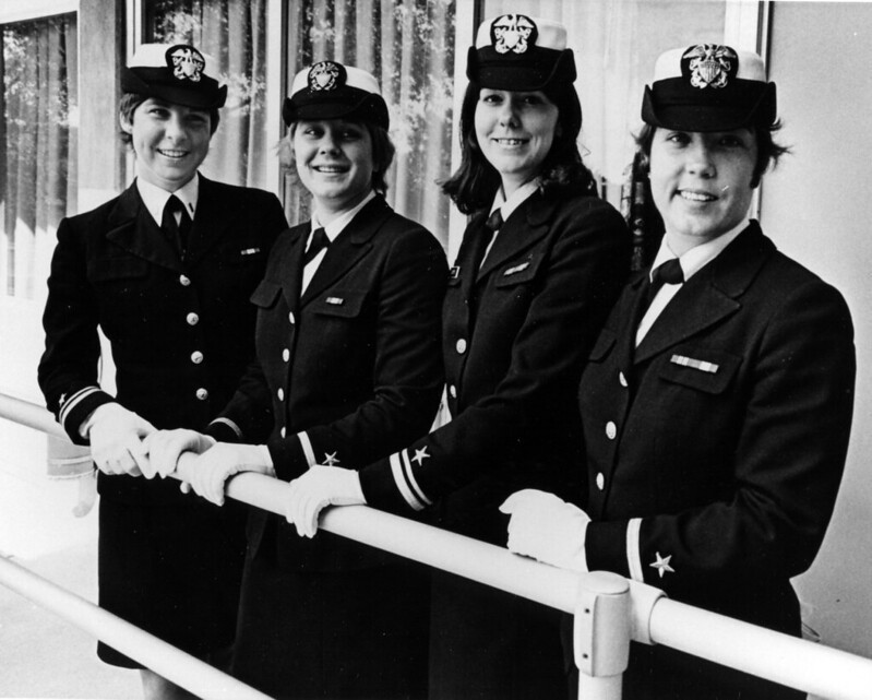 Four women in uniform standing along a handrail. 