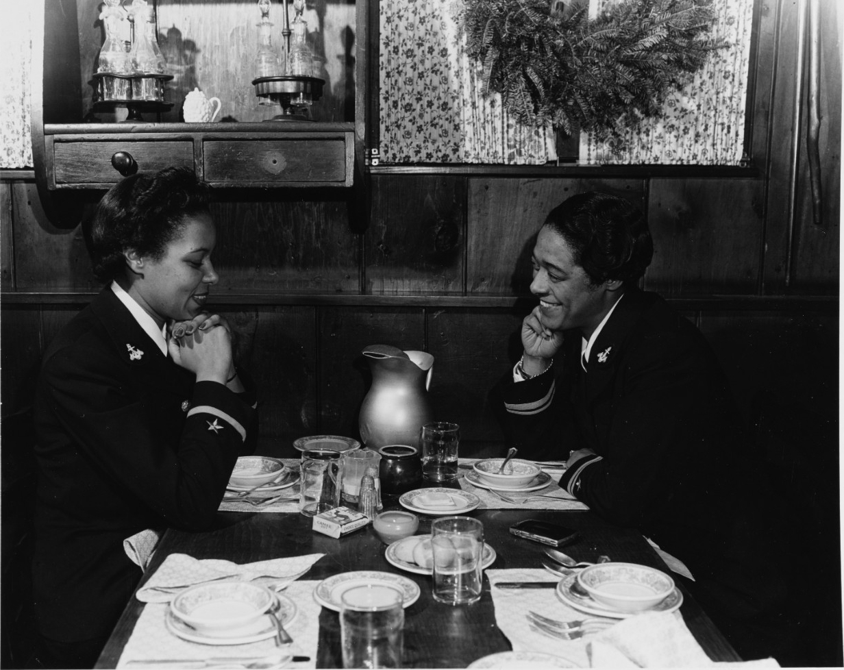 Two uniformed women sitting across a table from each other.