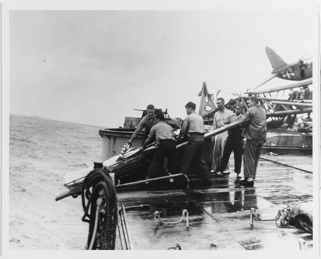 Burial at sea for crewmen killed when the ship was torpedoed off Formosa on 14 October 1944. Photographed while Houston was under tow on 15 October. 