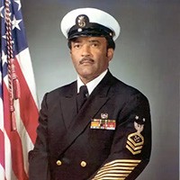 <p>Portrait of a black man in officer uniform with cover, U.S. flag in background.&nbsp;</p>