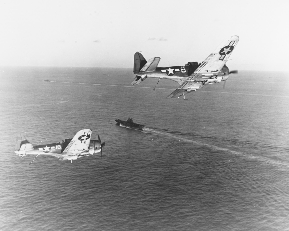 Two SBD-5 bombers turn into the landing pattern as they return to the carrier after strikes on the Palau Islands, 20-30 March 1944. Note tail hooks in down position.