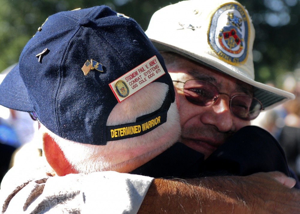 Former crew members of the guided-missile destroyer USS Cole embrace before the beginning of the tenth anniversary remembrance ceremony of the terrorist attack on Cole. The Norfolk-based ship was damaged by a suicide bombing while refueling in th...