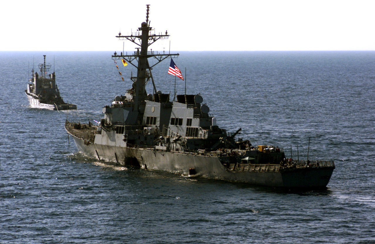 The crew of the Arleigh Burke-class USS Cole (DDG-67), escort their wounded ship aboard Navy tug vessel, USNS Catawba,