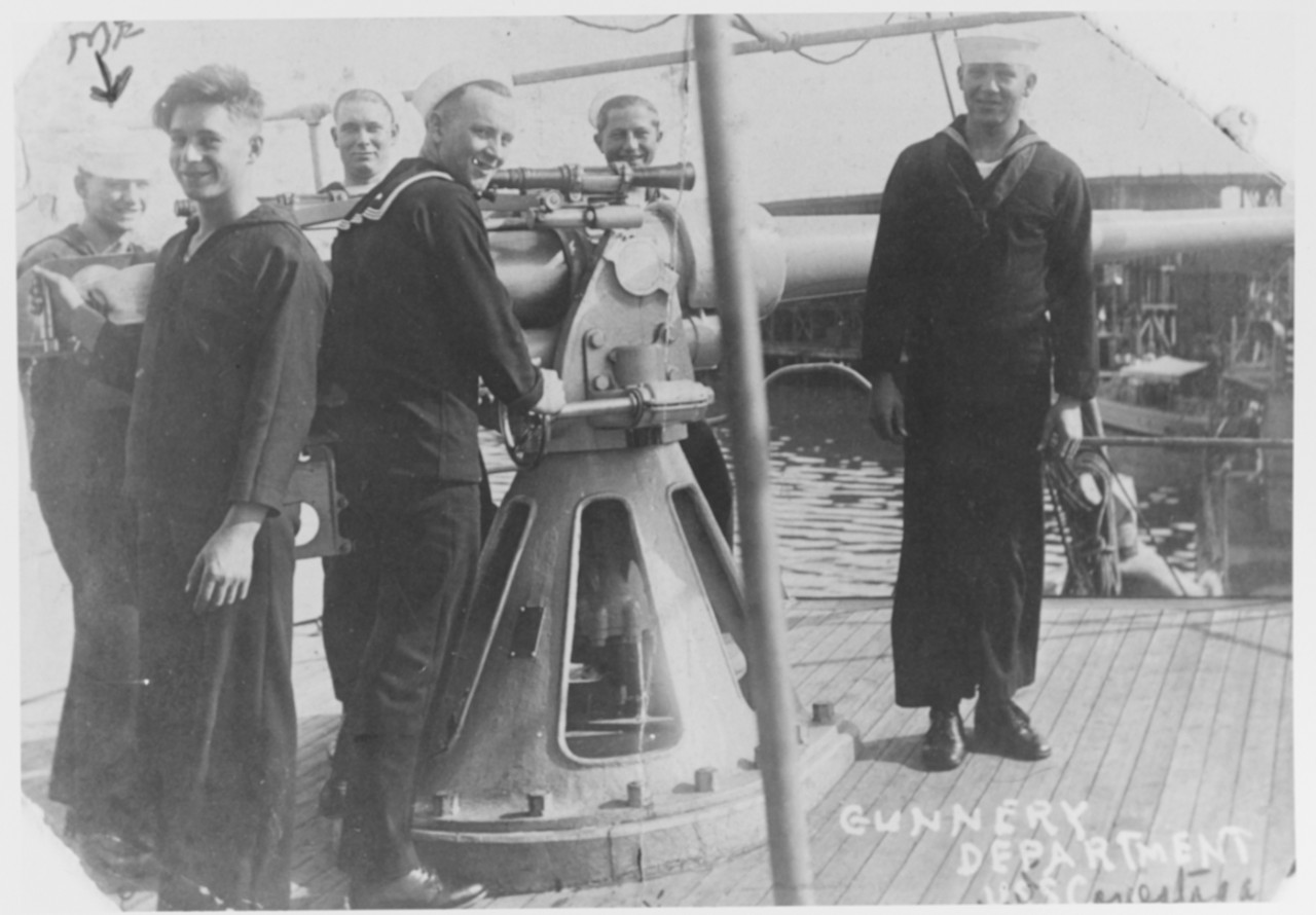 Sailors standing around gun on deck of ship