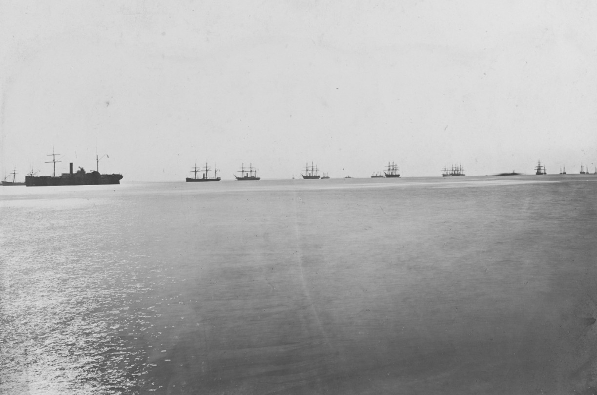 View of the open sea with black shilouettes of ships in the distance.