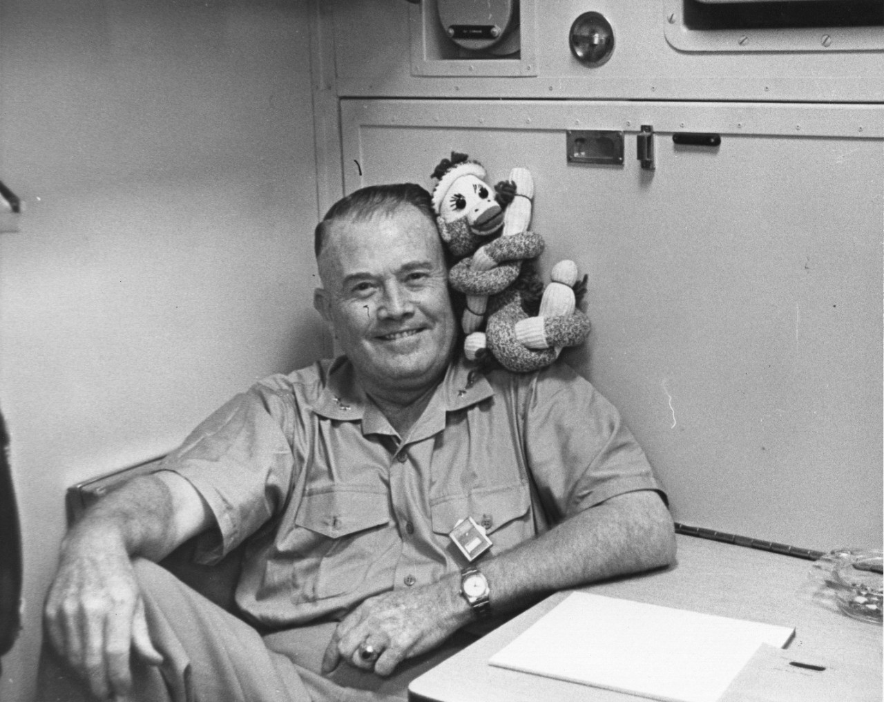 Rear Admiral William Raborn smiles with a sock monkey on his shoulder