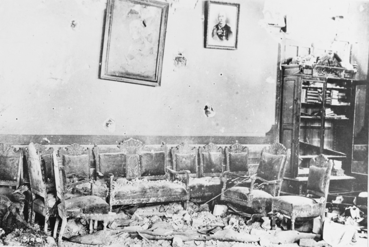 A shell-damaged room with pictures hanging askew. Clicking this image directs to a page to download the image.
