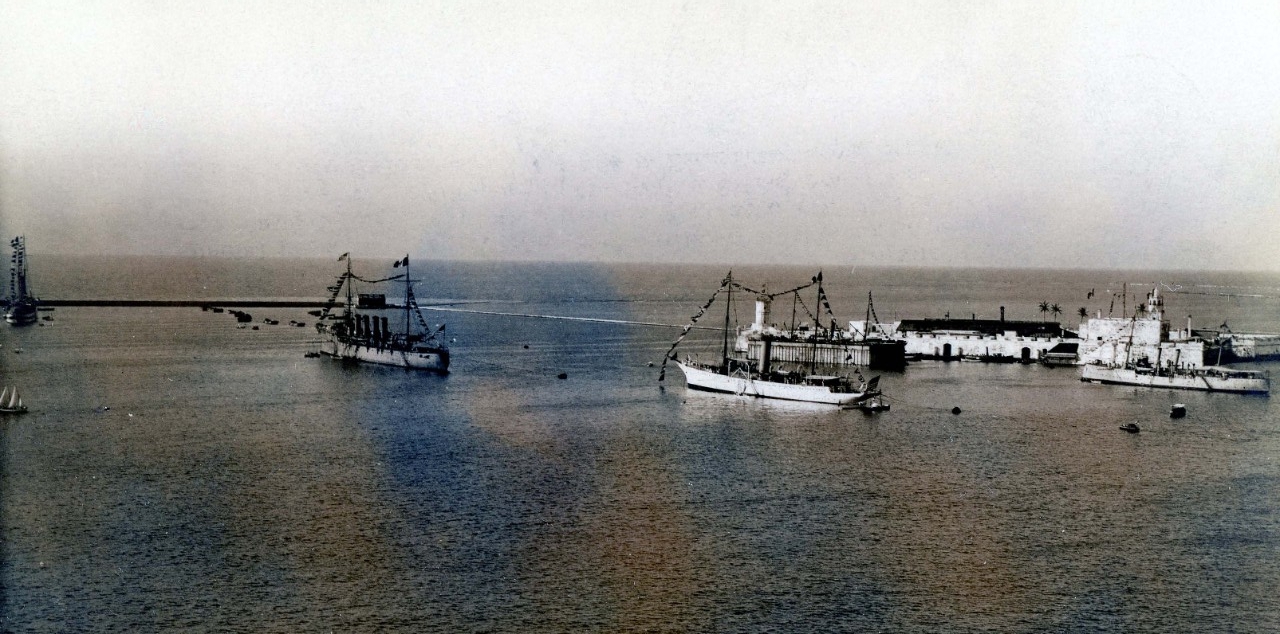Four ships in full dress in a harbor.