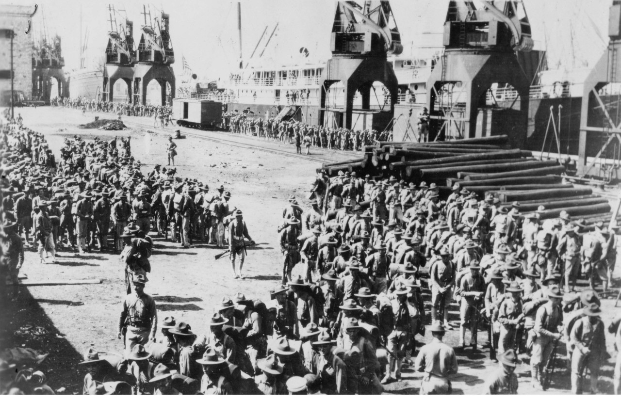 Hundreds of uniformed marines gathered by a docked ship.